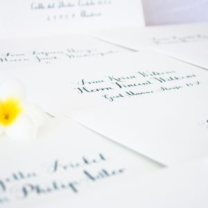 sobre blanco para eventos con caligrafía verde y flor